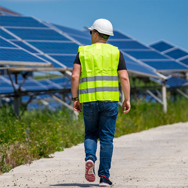 Worker in vest near solar panel